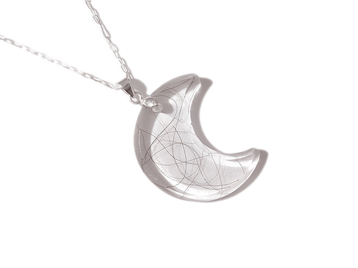 A clear moon shaped pendant with small amount of loved ones hair