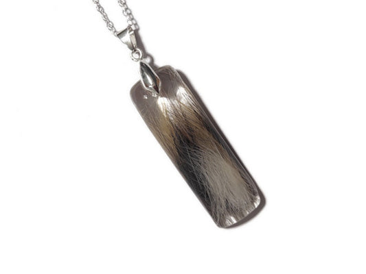 A handmade lock of hair memorial necklace with multicolored pet fur.