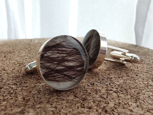 Cufflinks with hair inlay on a textured surface