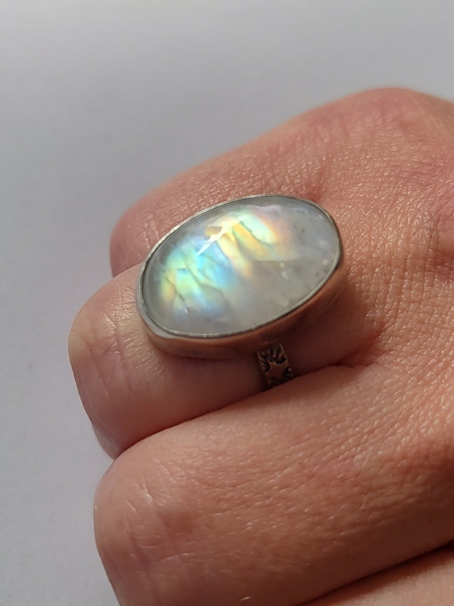 Rainbow moonstone ring being worn on a closed fist.