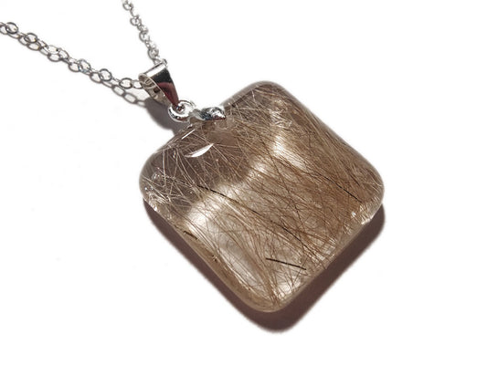 A small square pet memorial necklace containing hair, on a silver chain.