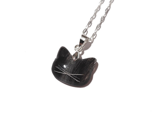A small cat shaped memorial necklace with a small amount of fur and whiskers.