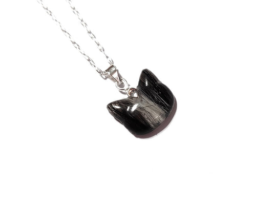 A small cat shaped memorial pendant with black and white pet fur.
