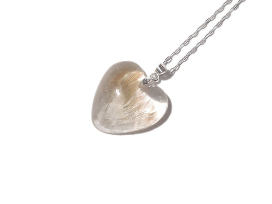 A heart shaped memorial necklace with beloved pet birds feathers.