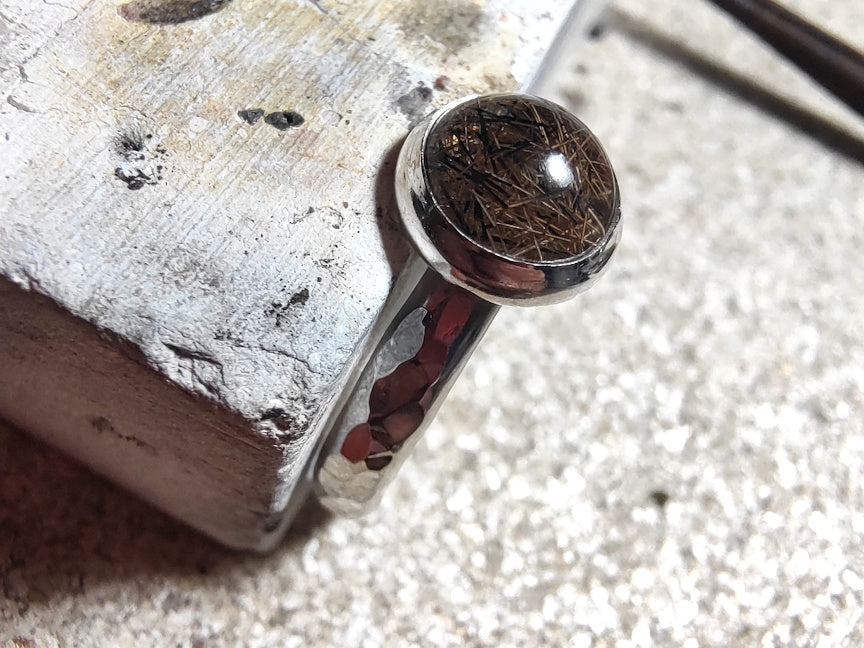 Close up of a keepsake ring, balanced on a soldering block of my silver bench.