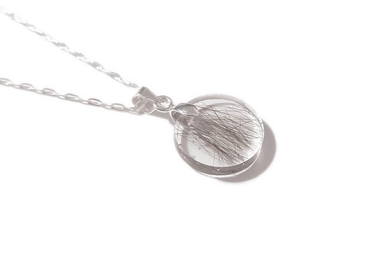 A handmade memorial necklace in the medallion shape, encasing a loved ones hair, fur, or ashes.