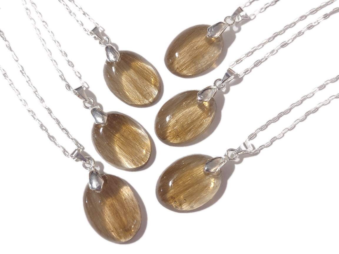 A group shot of 6 small oval shaped keepsake pendants with blonde hair.