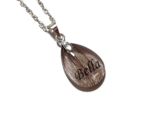 Resin pendant with 'Bella' name and pet fur on a silver chain against a white background