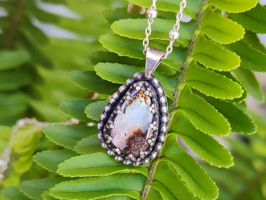 Handmade silver necklace with a pendant featuring a Yowah Boulder opal stone on green fern leaves.