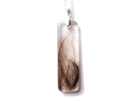 A handmade keepsake necklace in the bar shape with a loved ones hair, fur, or ashes.