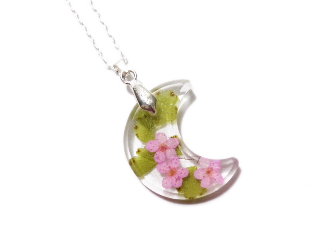 Handcrafted resin crescent moon necklace. Clear moon with three pink forget-me-not blossoms, over a sprig of maiden hair fern. On 18 inch silver chain.