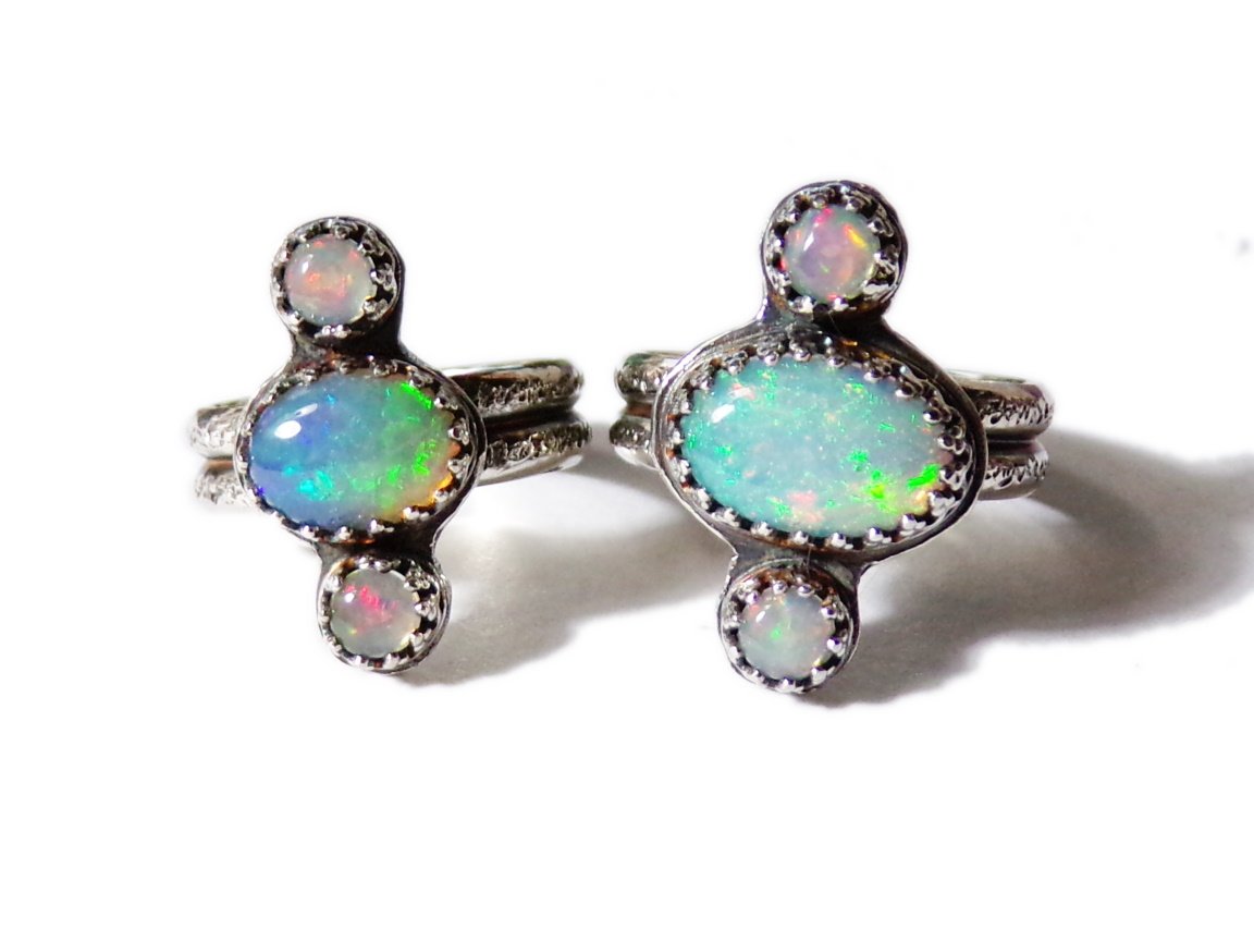Handsmithed sterling rings. Large ethiopian opal ovals in the middle, with smaller round welo opals on the norht and south of ring face. Double band with handstamped sand-grain texture.