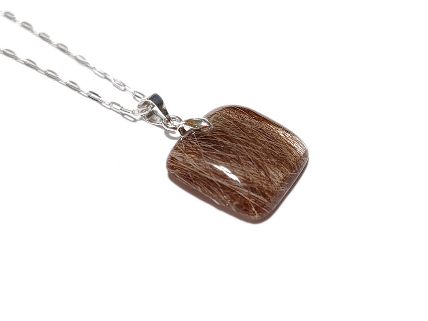 A small square pet memorial necklace containing hair, on a silver chain.