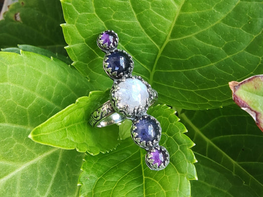 A handmade silver ring with moonstone, amethyst, and iolite gemstones.