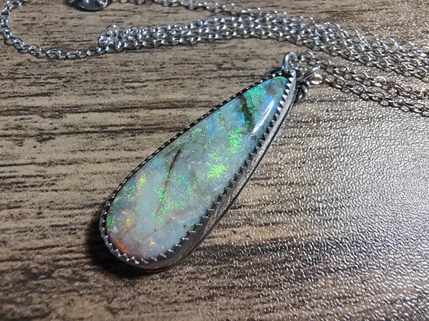 Opal pendant necklace on a wooden surface