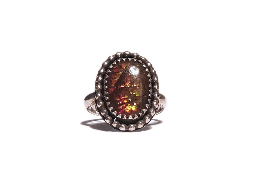 Ring with a large ammolite stone and silver band on a white background