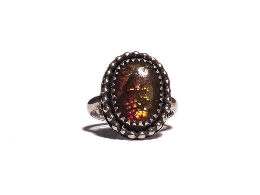 Ring with a large ammolite stone and silver band on a white background