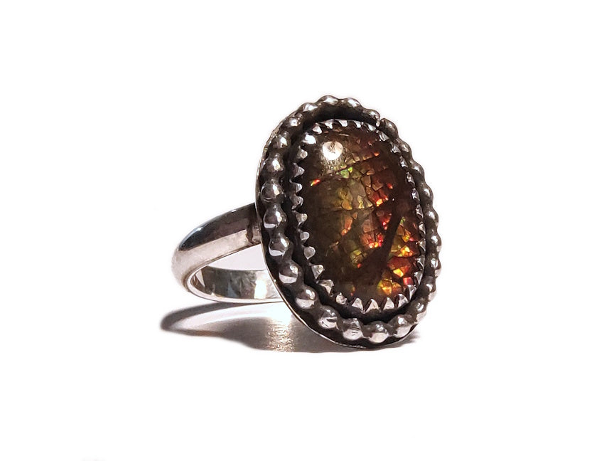 Silver ring with an ammolite gemstone on a white background