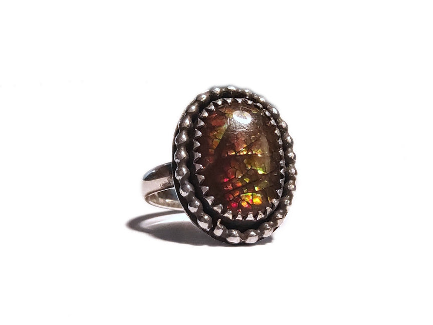 Ring with an ammolite gemstone and silver band on a white background
