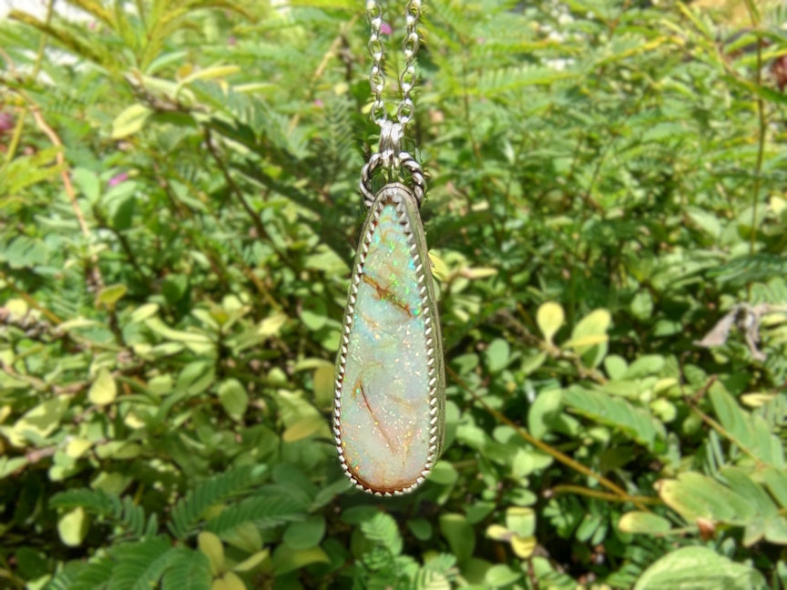 Necklace with a pendant hanging among green leaves