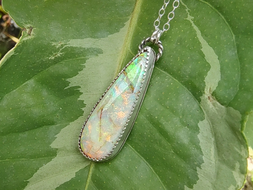 Opal pendant necklace on a green leaf background