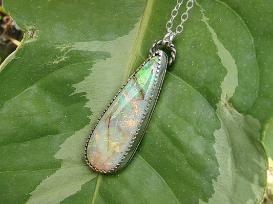 Opal pendant necklace on a green leaf