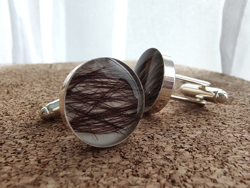 Cufflinks with hair inlay on a textured surface
