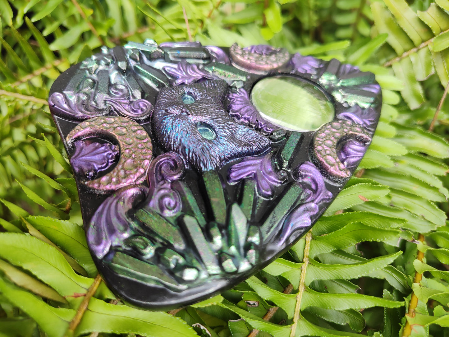 Decorative planchette with intricate patterns on a green leaf background