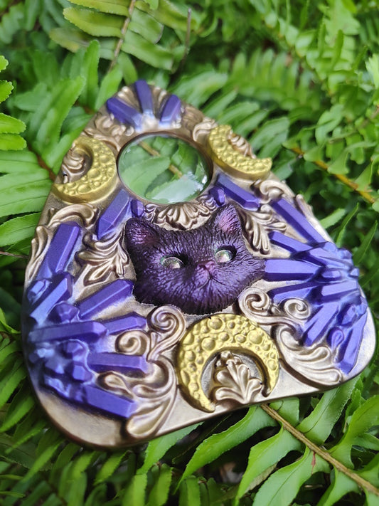Decorative planchette with a purple cat design on a green leaf background