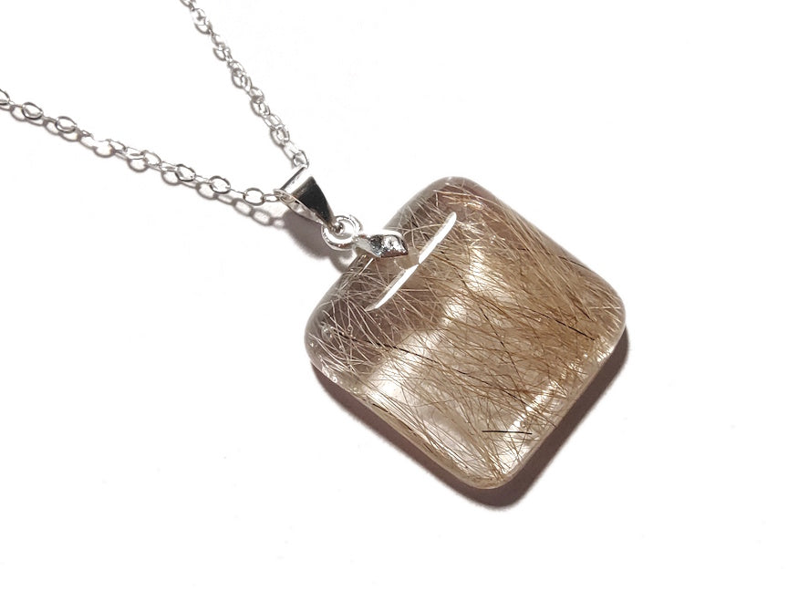 A small square pet memorial necklace containing hair, on a silver chain.