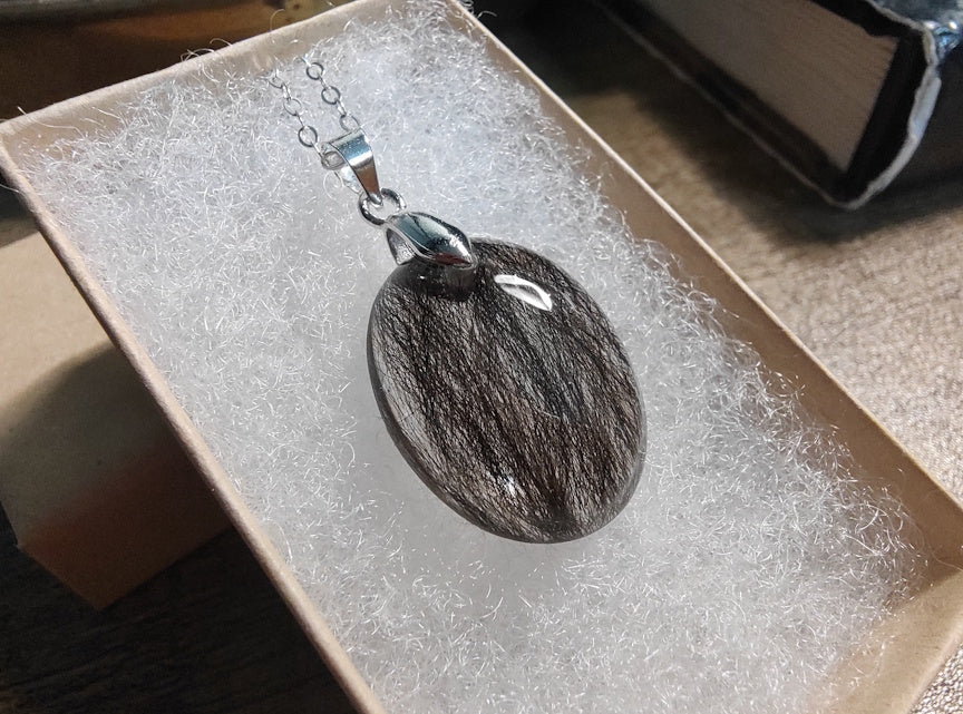 A hair lock necklace in a giftbox, on silver chain.