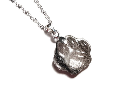 Pet fur memorial necklace in the shape of a paw print.