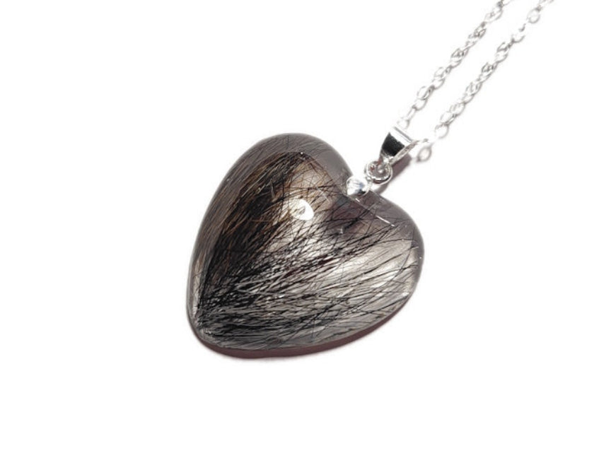 Heart-shaped hair locket pendant on a chain against a white background