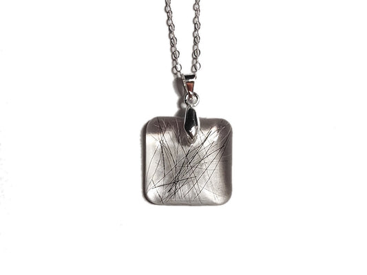 A memorial necklace with a small amount of black hair, on a silver chain.