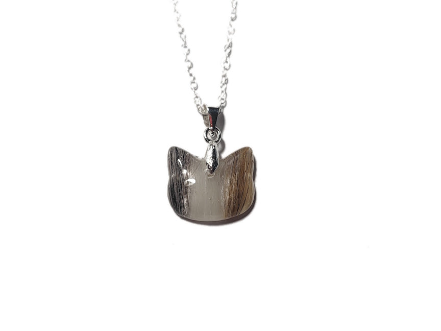 A cat keepsake necklace with orange, white, and black cat fur.