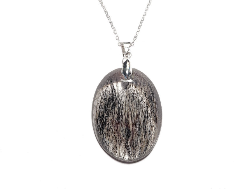 An oval shaped keepsake necklace encasing a pets fur, on a silver chain. 
