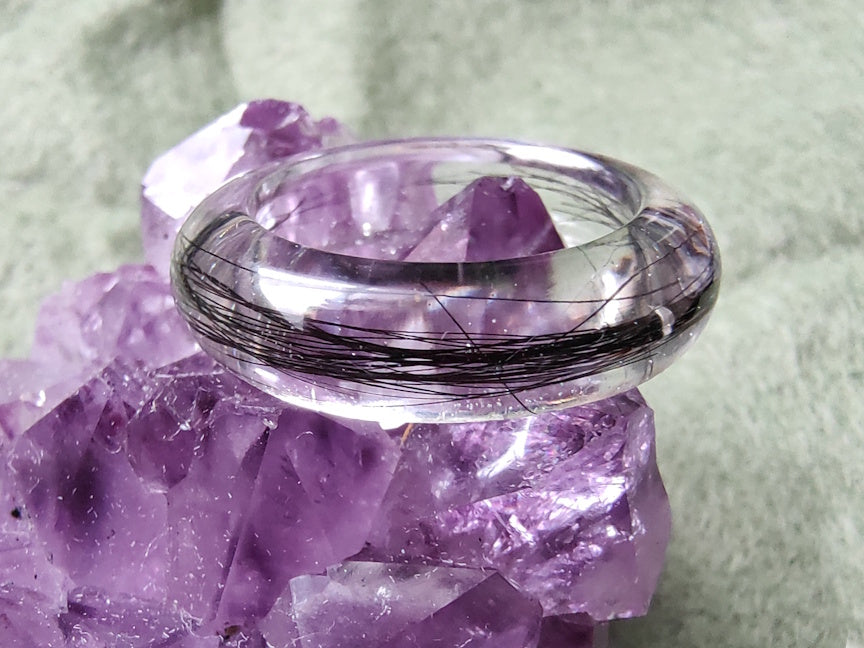 A clear resin memorial ring with black hair, atop a purple crystal.