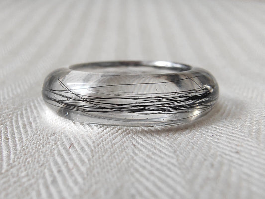 Close up view of a clear resin keepsake ring with black hair.