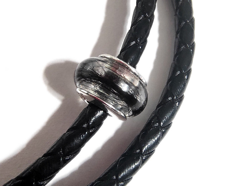 close up of a keepsake bead on a braided leather bracelet