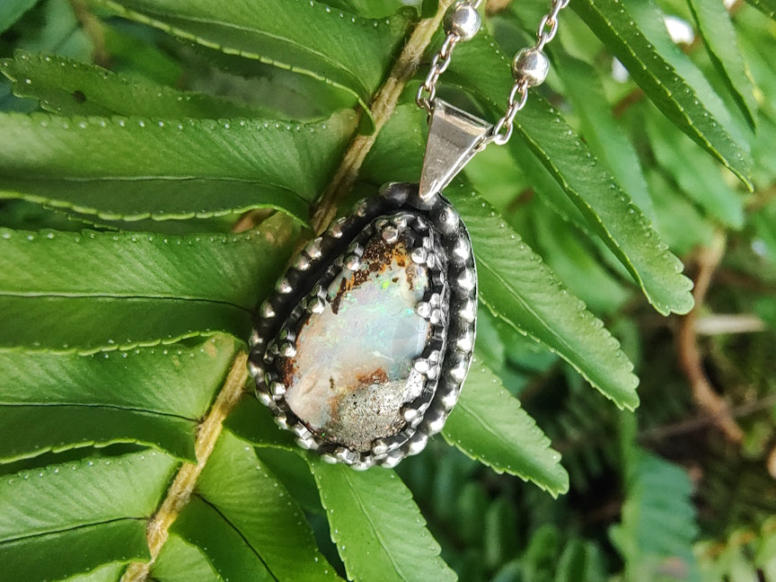 Handmade silver necklace with a pendant featuring a Yowah Boulder  opal stone on green fern leaves.