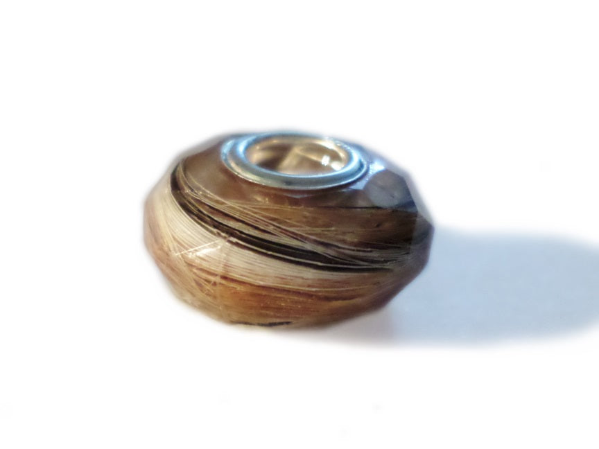 A close up of a faceted euro bead containing fur