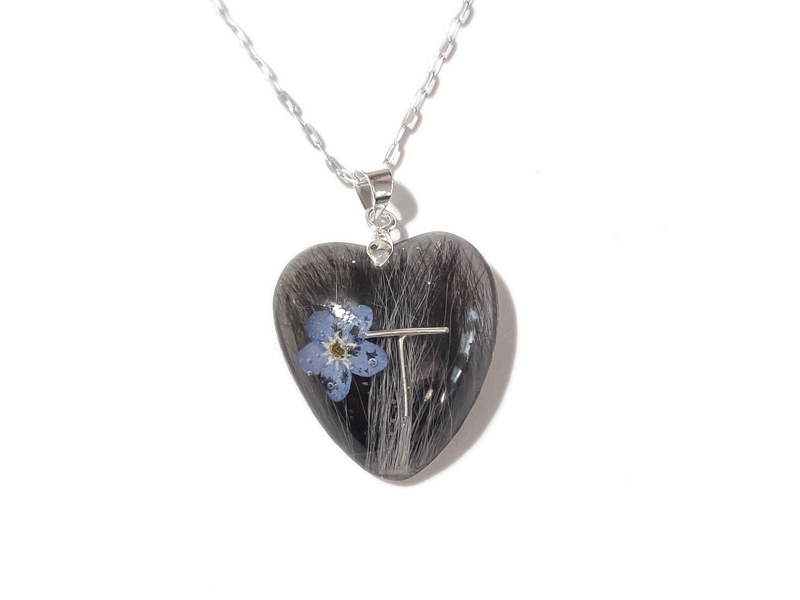 A handmade keepsake necklace in the heart shape with a loved ones hair, fur, or ashes.