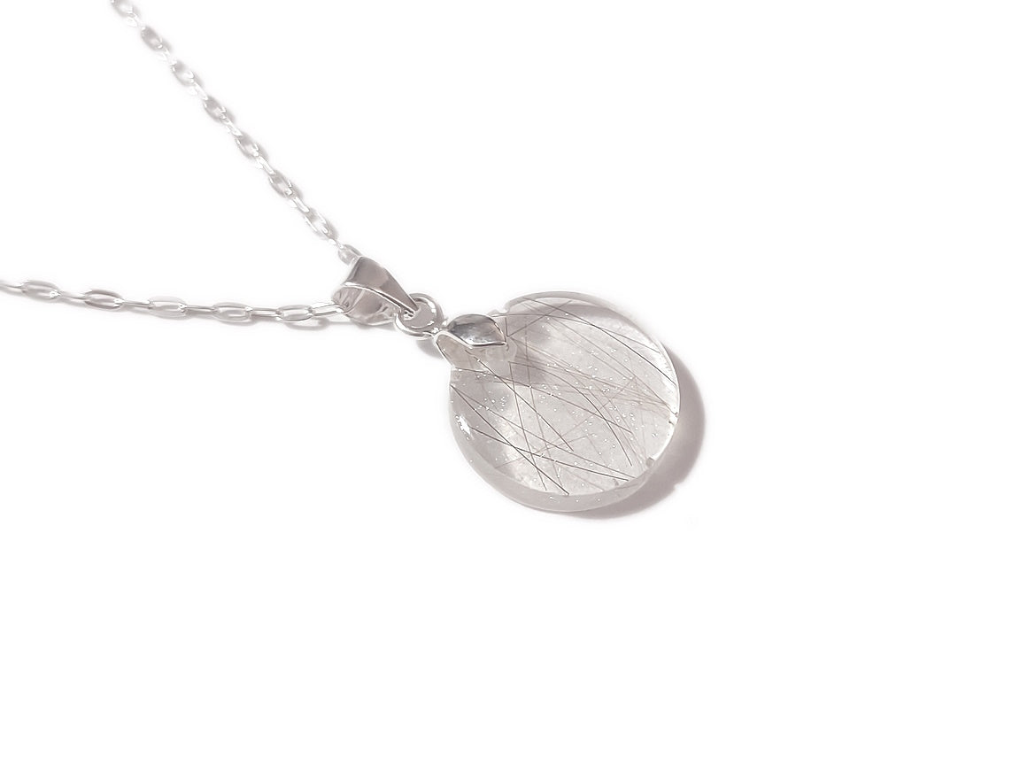 A handmade memorial necklace in the medallion shape, encasing a loved ones hair, fur, or ashes. 