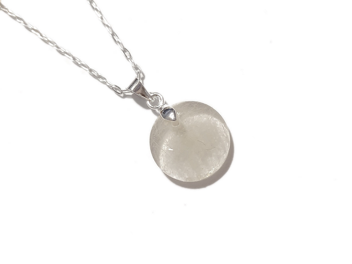 A handmade memorial necklace in the medallion shape, encasing a loved ones hair, fur, or ashes. 