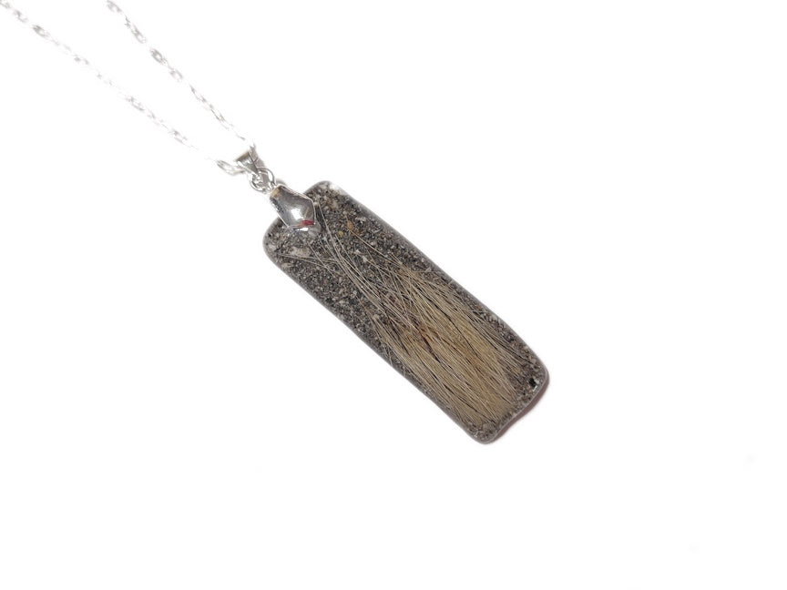 A bar style memorial pendant with hair and ashes.