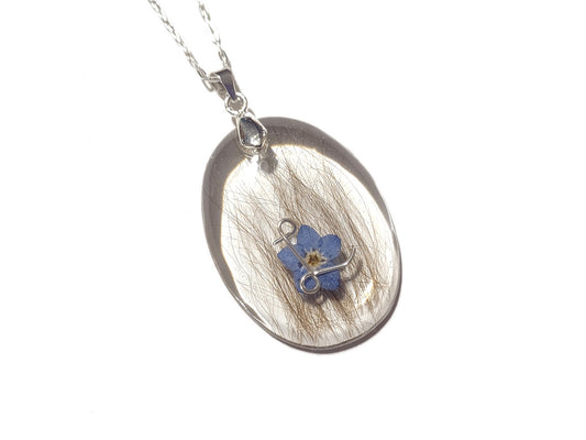 large oval hair locket memorial necklace including hair, initial, and forget me not flower. 