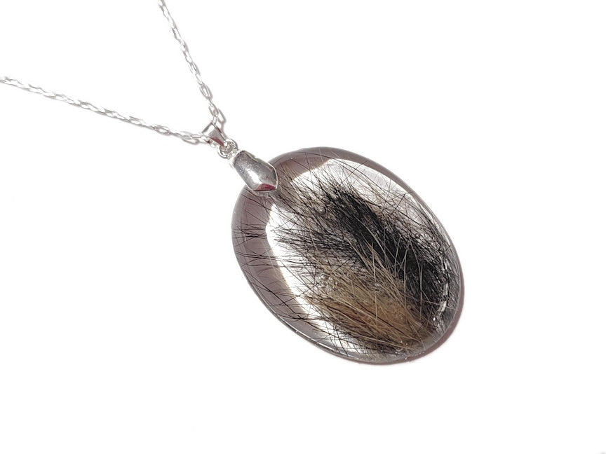 a large oval memorial pendant with two colors of hair inside