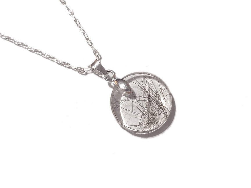 a small medallion keepsake necklace with a scattering of dark hair