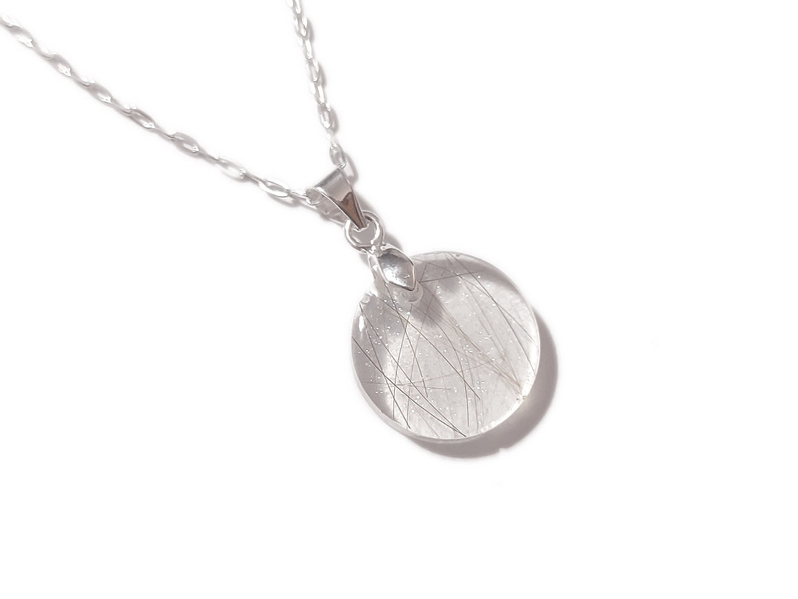 A handmade memorial necklace in the medallion shape, encasing a loved ones hair, fur, or ashes. 