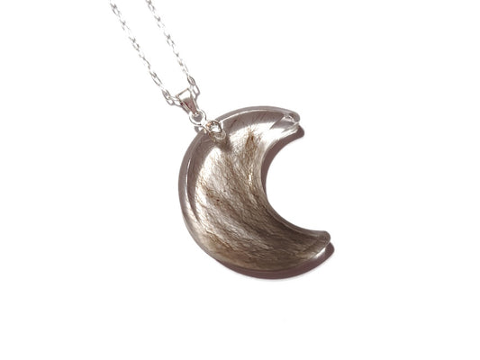 A handmade crescent moon shaped memorial or keepsake necklace with hair or fur